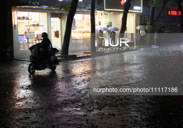 People are riding electric bikes on a street during heavy rain in Nanchang, Jiangxi Province, China, on April 2, 2024. 