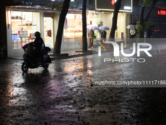 People are riding electric bikes on a street during heavy rain in Nanchang, Jiangxi Province, China, on April 2, 2024. (