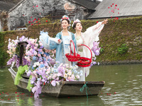 Women dressed as silkworm flowers are throwing silkworm flowers to a silkworm farmer on a boat to pray for a bumper harvest in Huzhou, China...