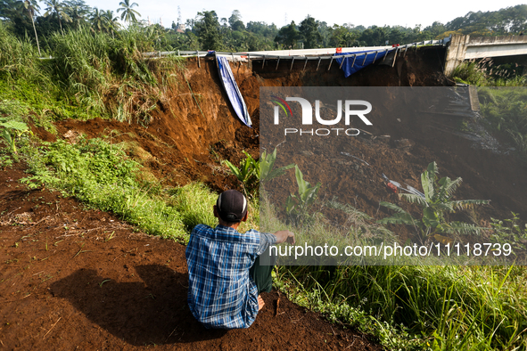 Residents are sitting and looking at the Bogor-Ciawi-Sukabumi (Bocimi) Toll Road after it was hit by a landslide in Bogor, Indonesia, on Apr...