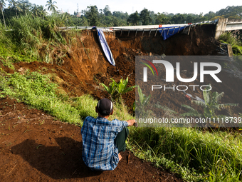 Residents are sitting and looking at the Bogor-Ciawi-Sukabumi (Bocimi) Toll Road after it was hit by a landslide in Bogor, Indonesia, on Apr...