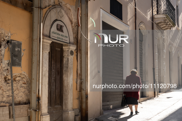 A woman walking next to damaged and rebuilt buildings is seen in L'Aquila, Italy, on April 5th, 2024. on April 6th L'Aquila will commemorate...