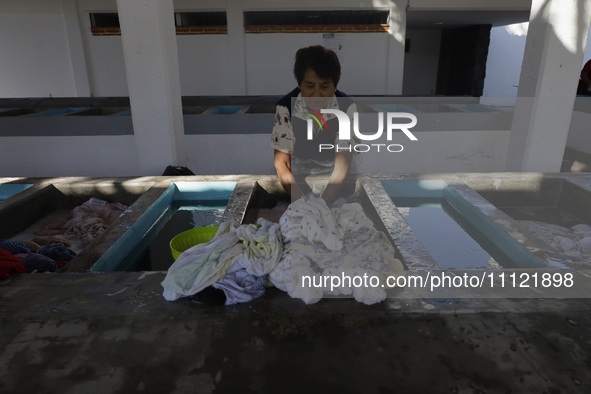 A woman is washing clothes at a community laundry in Santa Cruz Acalpixca, Xochimilco, Mexico City. 