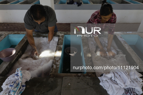 Two people are washing clothes at a community laundry in Santa Cruz Acalpixca, Xochimilco, Mexico City. 