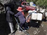 A person is filling water drums that are being transported by donkeys in Santa Cruz Acalpixca, Xochimilco, in Mexico City, due to a shortage...