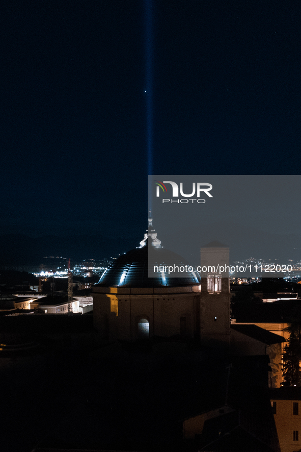 A blue light beam faced to the sky and San Bernardino church dome are seen in an aerial view in L'Aquila, Italy, on April 5th, 2024. On Apri...