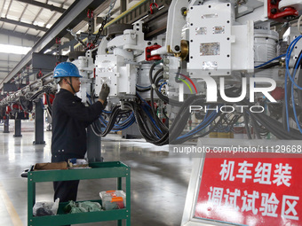 A technician is unveiling a newly assembled locomotive at a workshop of an equipment manufacturing company in Zaozhuang, China, on April 7,...