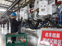 A technician is unveiling a newly assembled locomotive at a workshop of an equipment manufacturing company in Zaozhuang, China, on April 7,...