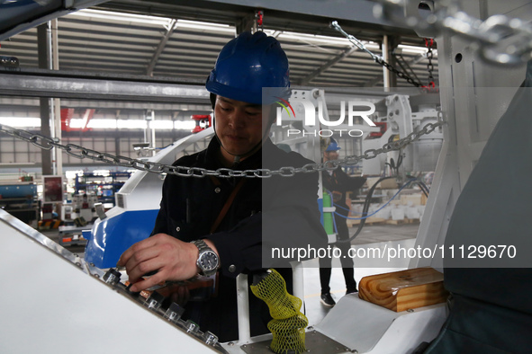 A technician is unveiling a newly assembled locomotive at a workshop of an equipment manufacturing company in Zaozhuang, China, on April 7,...