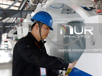 A technician is unveiling a newly assembled locomotive at a workshop of an equipment manufacturing company in Zaozhuang, China, on April 7,...