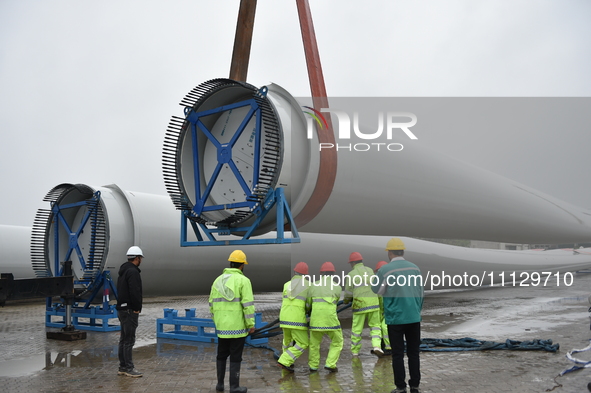 A crane is lifting wind turbine blades onto a special transport vehicle in Yangzhou, East China's Jiangsu province, on April 8, 2024. 