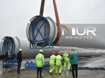 A crane is lifting wind turbine blades onto a special transport vehicle in Yangzhou, East China's Jiangsu province, on April 8, 2024. (