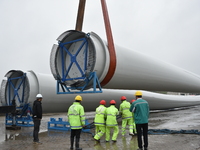 A crane is lifting wind turbine blades onto a special transport vehicle in Yangzhou, East China's Jiangsu province, on April 8, 2024. (