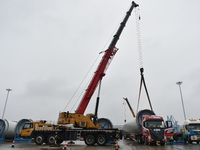 A crane is lifting wind turbine blades onto a special transport vehicle in Yangzhou, East China's Jiangsu province, on April 8, 2024. (