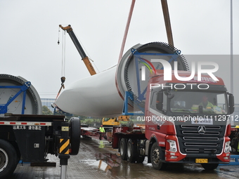 A crane is lifting wind turbine blades onto a special transport vehicle in Yangzhou, East China's Jiangsu province, on April 8, 2024. (