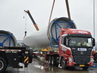 A crane is lifting wind turbine blades onto a special transport vehicle in Yangzhou, East China's Jiangsu province, on April 8, 2024. (