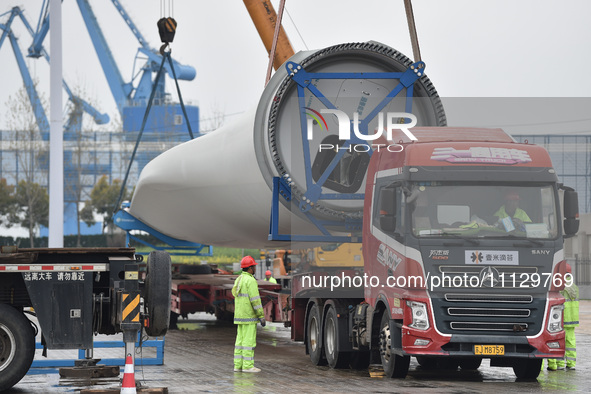 A crane is lifting wind turbine blades onto a special transport vehicle in Yangzhou, East China's Jiangsu province, on April 8, 2024. 