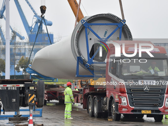 A crane is lifting wind turbine blades onto a special transport vehicle in Yangzhou, East China's Jiangsu province, on April 8, 2024. (