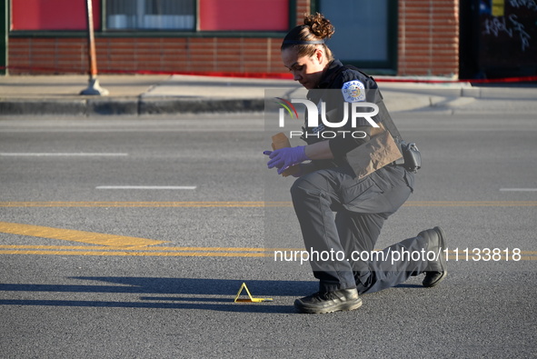 A police officer is collecting evidence at the crime scene where a 4-year-old boy is in critical condition after being shot in broad dayligh...