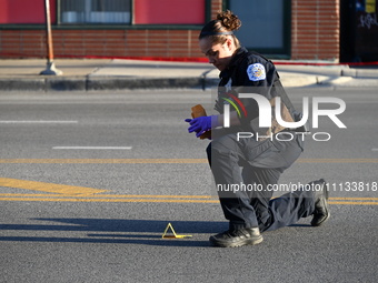 A police officer is collecting evidence at the crime scene where a 4-year-old boy is in critical condition after being shot in broad dayligh...