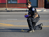 A police officer is collecting evidence at the crime scene where a 4-year-old boy is in critical condition after being shot in broad dayligh...