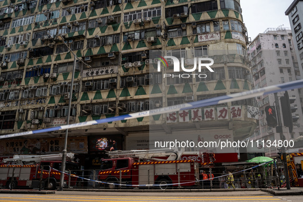 A general view is showing a police cordon line in front of a building that is on fire with fire trucks parked below it in Hong Kong, on Apri...