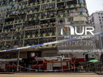 A general view is showing a police cordon line in front of a building that is on fire with fire trucks parked below it in Hong Kong, on Apri...