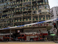 A general view is showing a police cordon line in front of a building that is on fire with fire trucks parked below it in Hong Kong, on Apri...