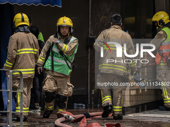 Firefighters are near the scene of a building fire in Hong Kong's Jordan District on April 10, 2024. The fire is resulting in 5 deaths and m...