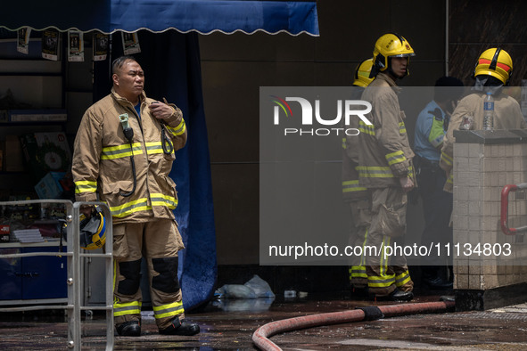 Firefighters are near the scene of a building fire in Hong Kong's Jordan District on April 10, 2024. The fire is resulting in 5 deaths and m...