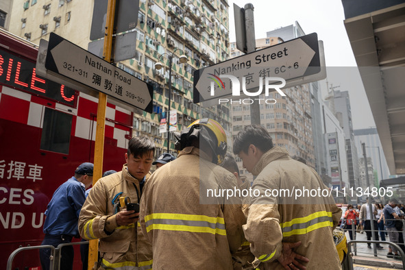 Firefighters are near the scene of a building fire in Hong Kong's Jordan District on April 10, 2024. The fire is resulting in 5 deaths and m...