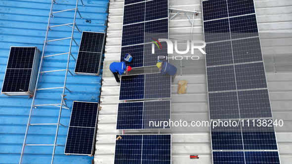 Workers are installing solar photovoltaic panels on the roof of a factory in Haian, Jiangsu Province, China, on April 11, 2024. 