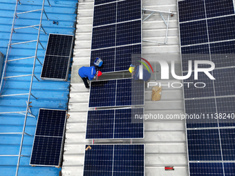 Workers are installing solar photovoltaic panels on the roof of a factory in Haian, Jiangsu Province, China, on April 11, 2024. (