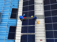 Workers are installing solar photovoltaic panels on the roof of a factory in Haian, Jiangsu Province, China, on April 11, 2024. (