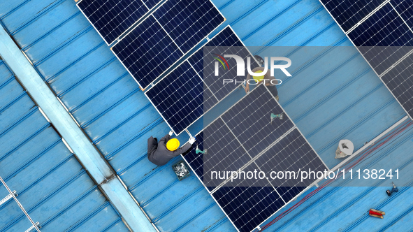 Workers are installing solar photovoltaic panels on the roof of a factory in Haian, Jiangsu Province, China, on April 11, 2024. 