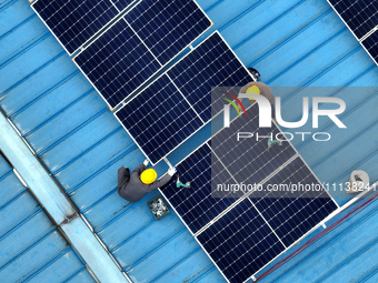 Workers are installing solar photovoltaic panels on the roof of a factory in Haian, Jiangsu Province, China, on April 11, 2024. (