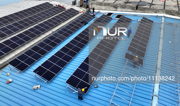 Workers are installing solar photovoltaic panels on the roof of a factory in Haian, Jiangsu Province, China, on April 11, 2024. 