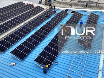 Workers are installing solar photovoltaic panels on the roof of a factory in Haian, Jiangsu Province, China, on April 11, 2024. (