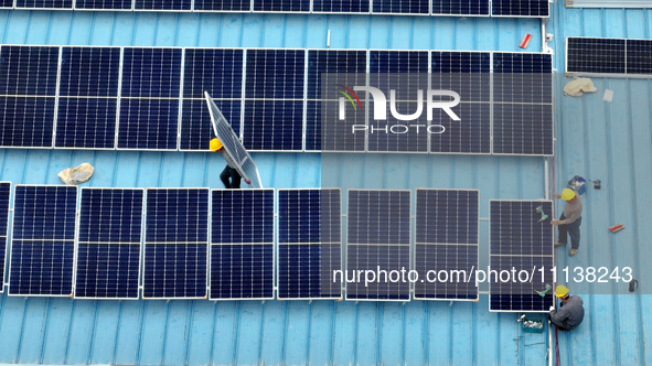 Workers are installing solar photovoltaic panels on the roof of a factory in Haian, Jiangsu Province, China, on April 11, 2024. 