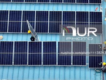 Workers are installing solar photovoltaic panels on the roof of a factory in Haian, Jiangsu Province, China, on April 11, 2024. (