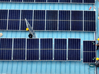 Workers are installing solar photovoltaic panels on the roof of a factory in Haian, Jiangsu Province, China, on April 11, 2024. (