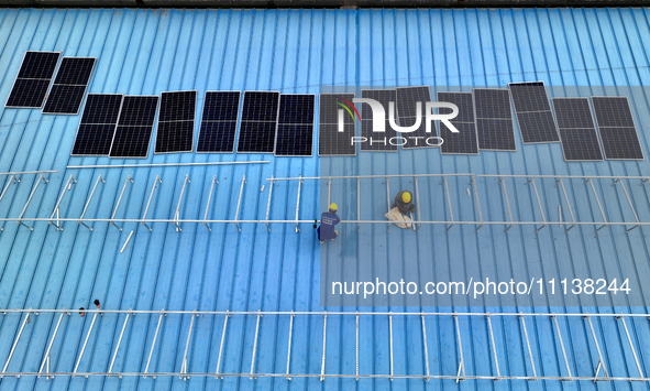 Workers are installing solar photovoltaic panels on the roof of a factory in Haian, Jiangsu Province, China, on April 11, 2024. 