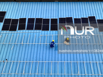 Workers are installing solar photovoltaic panels on the roof of a factory in Haian, Jiangsu Province, China, on April 11, 2024. (