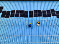 Workers are installing solar photovoltaic panels on the roof of a factory in Haian, Jiangsu Province, China, on April 11, 2024. (