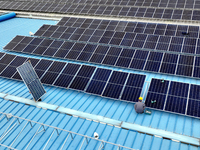 Workers are installing solar photovoltaic panels on the roof of a factory in Haian, Jiangsu Province, China, on April 11, 2024. (