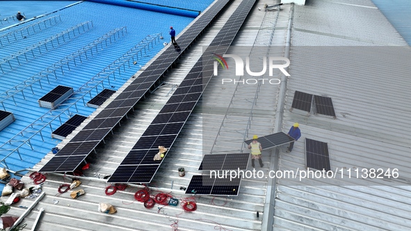 Workers are installing solar photovoltaic panels on the roof of a factory in Haian, Jiangsu Province, China, on April 11, 2024. 