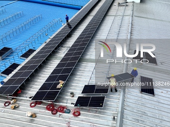 Workers are installing solar photovoltaic panels on the roof of a factory in Haian, Jiangsu Province, China, on April 11, 2024. (