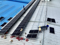 Workers are installing solar photovoltaic panels on the roof of a factory in Haian, Jiangsu Province, China, on April 11, 2024. (