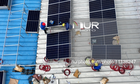 Workers are installing solar photovoltaic panels on the roof of a factory in Haian, Jiangsu Province, China, on April 11, 2024. 