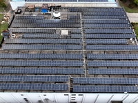 Workers are installing solar photovoltaic panels on the roof of a factory in Haian, Jiangsu Province, China, on April 11, 2024. (